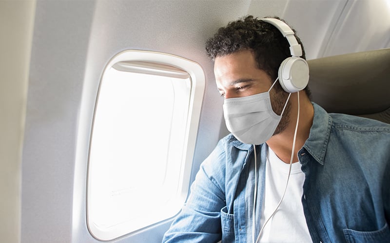 Hombre con mascarilla a bordo de un avión