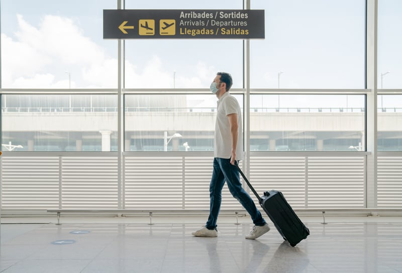 Viajero con mascarilla caminando por aeropuerto