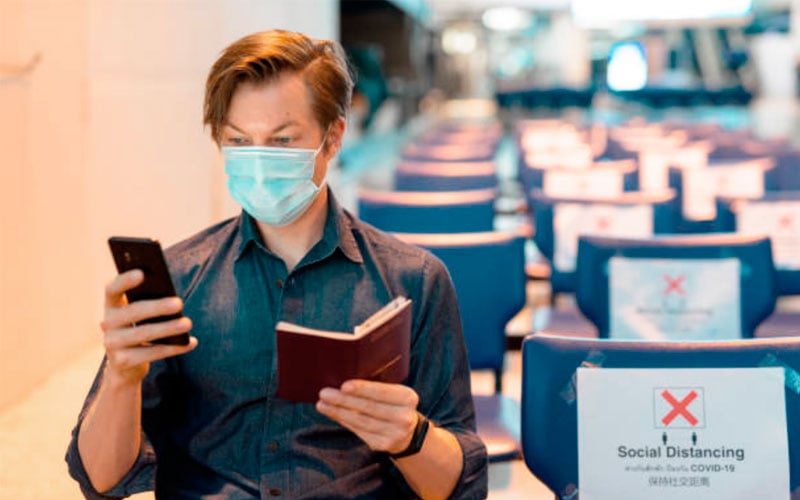 Viajero en aeropuerto con mascarilla y pasaporte