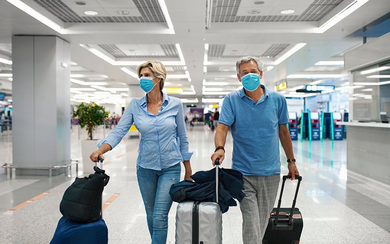 Viajeros en aeropuerto con mascarilla